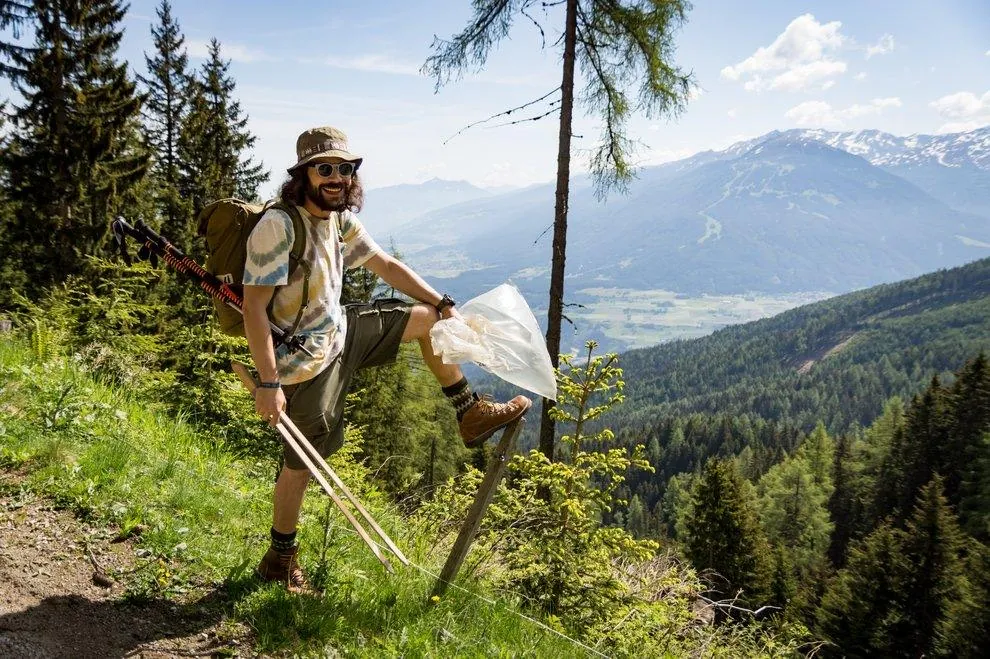 Wanderer mit Abfallsack vor einem Bergpanorama