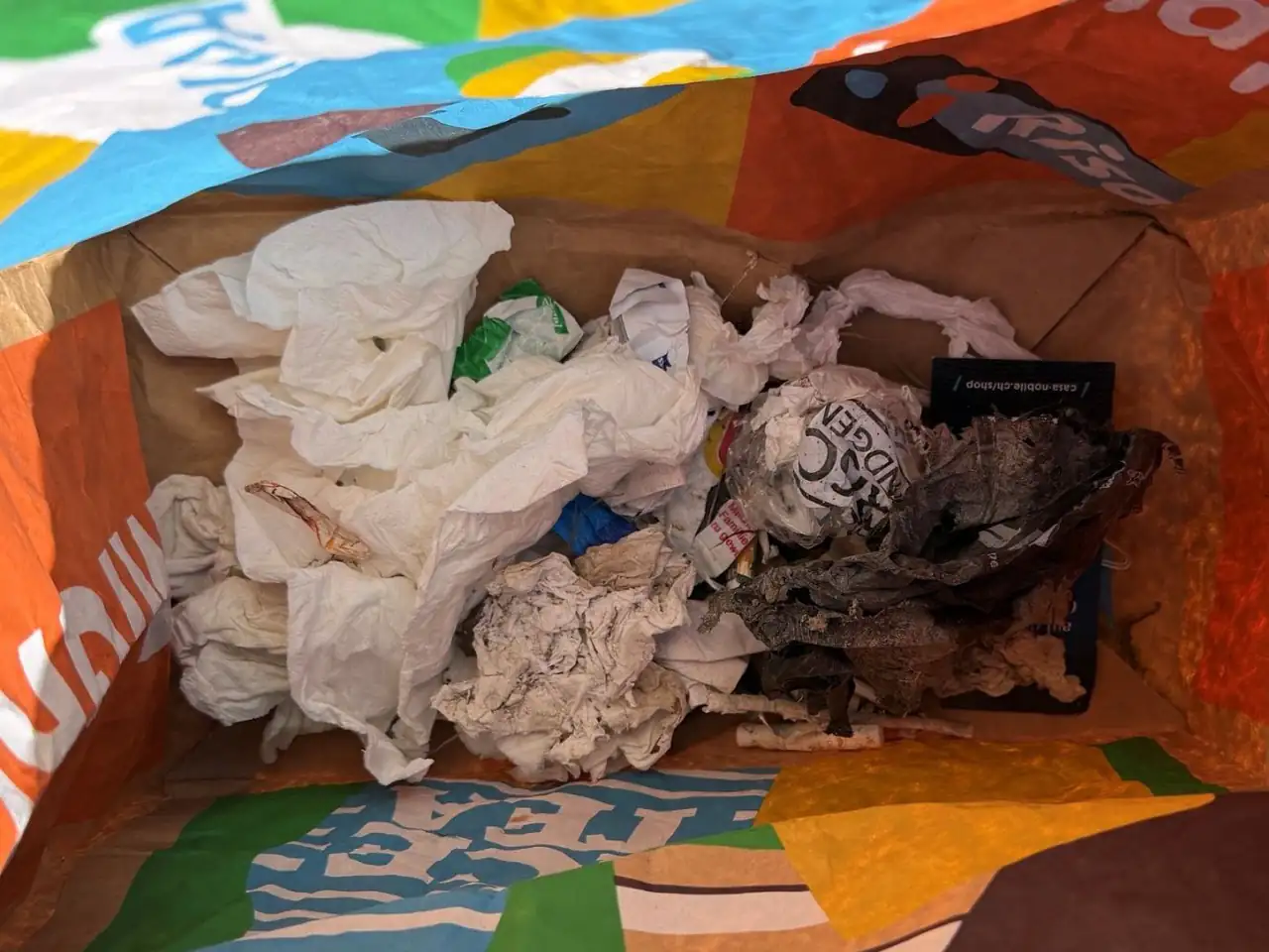 Tragtasche mit eingesammeltem Abfall, vor allem Papiertaschentücher und Plastikfolie